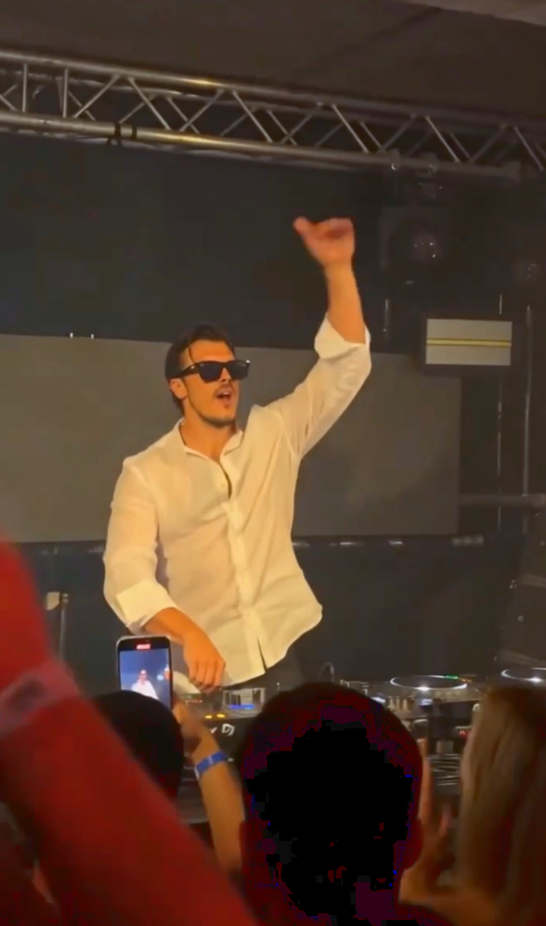 ROOM:SRVC DJ Sascha raising his hand toward a dancing club crowd