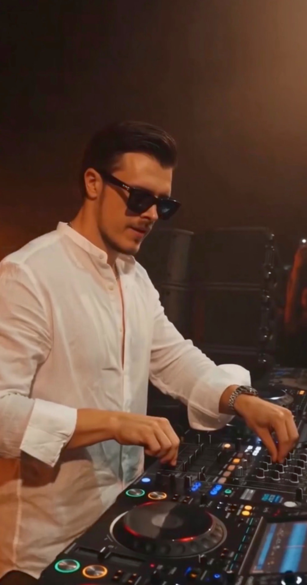 ROOM:SRVC DJ Sascha working the mixer during a live set in warm club light